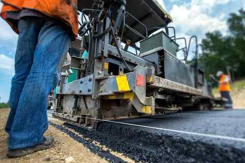 Workers monitoring an asphalt paving engine